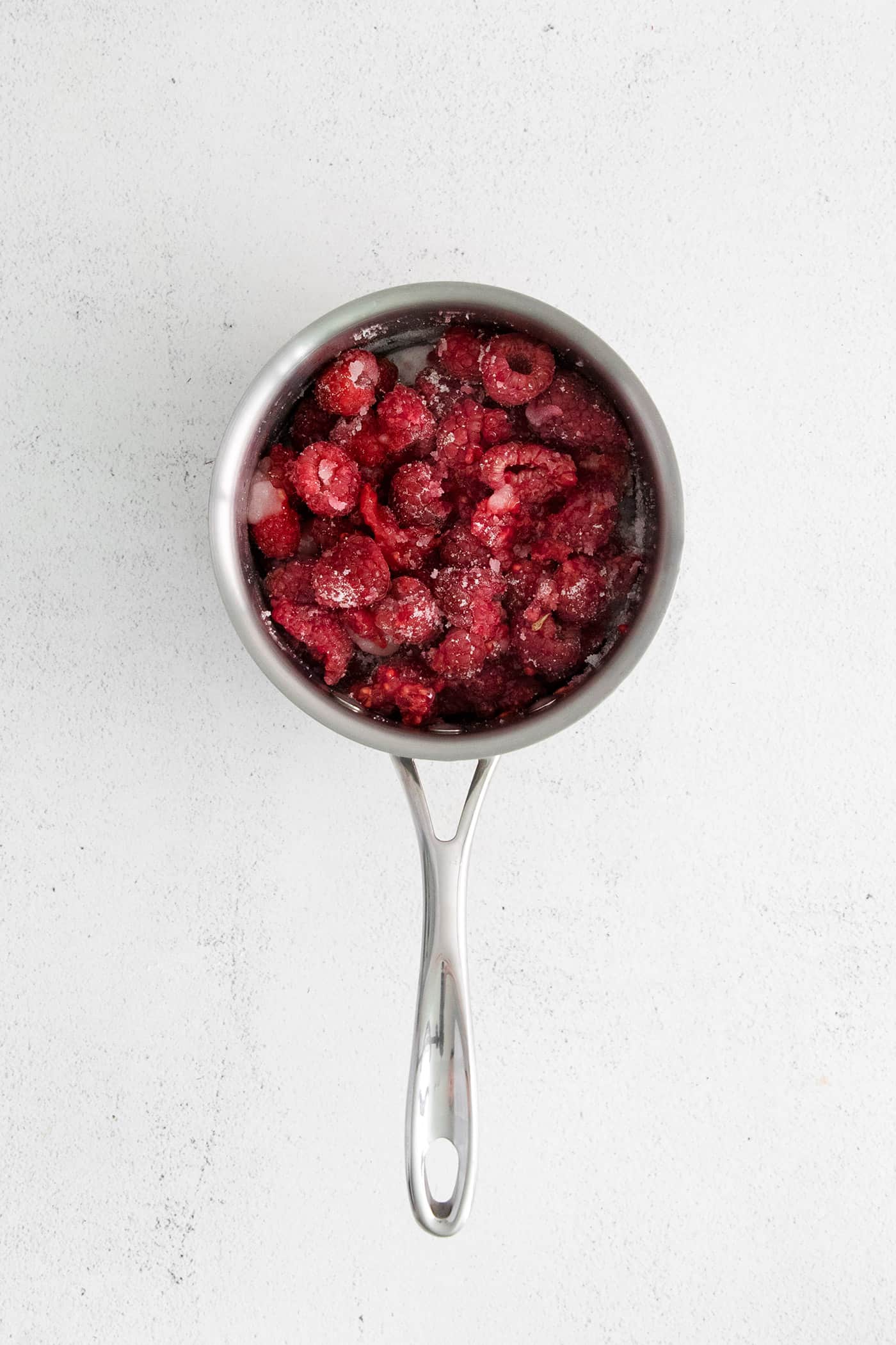 Raspberries with lime juice and sugar in a sauce pan
