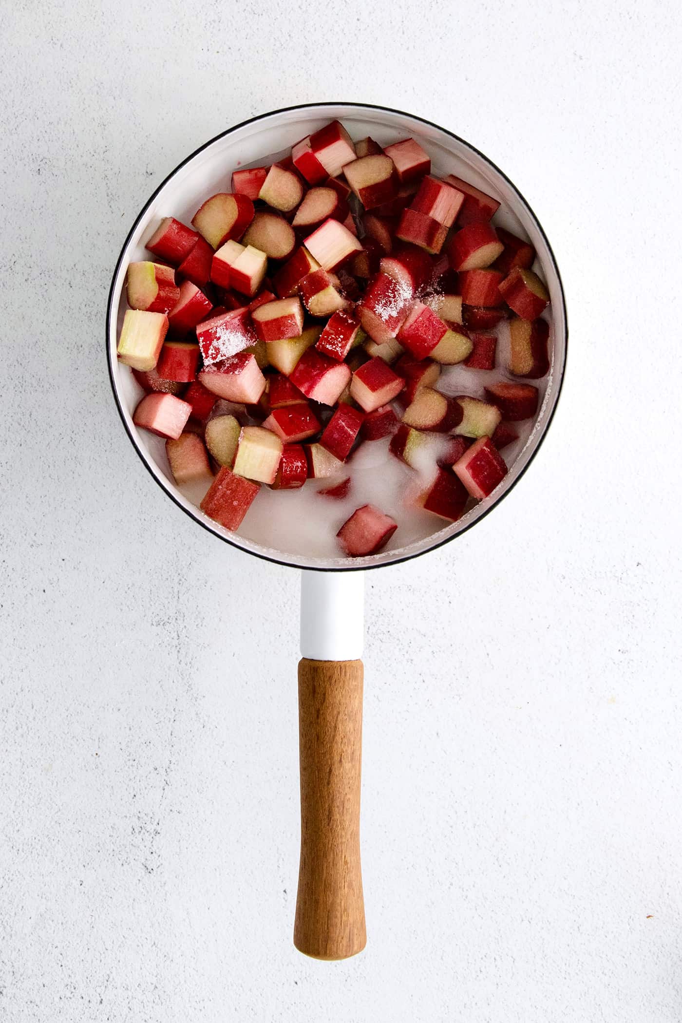 Pieces of rhubarb and sugar in a sauce pan