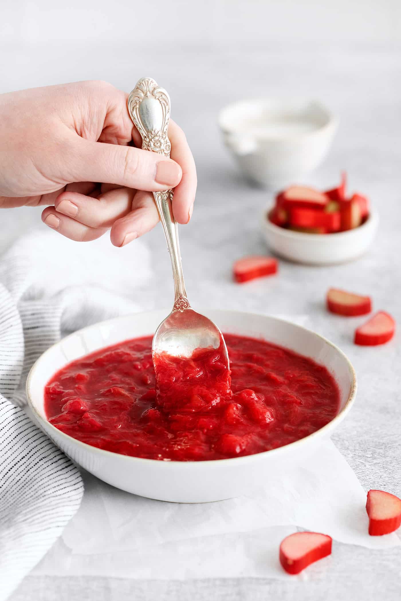 A spoon stirring a bowl of rhubarb sauce