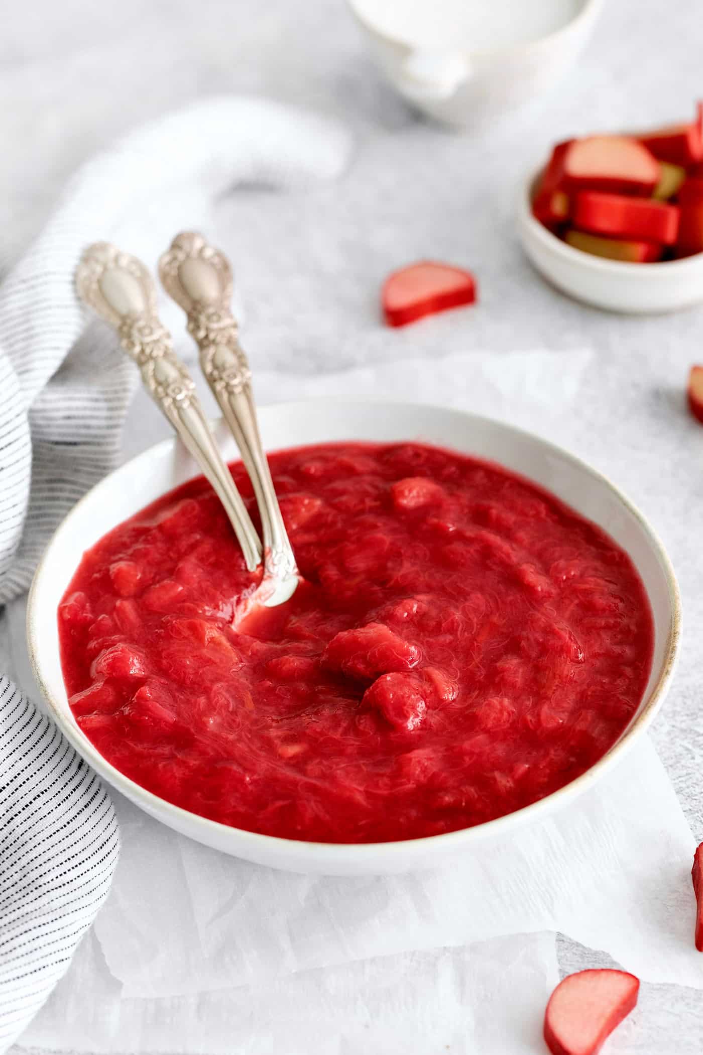 Two spoons in a bowl of rhubarb sauce