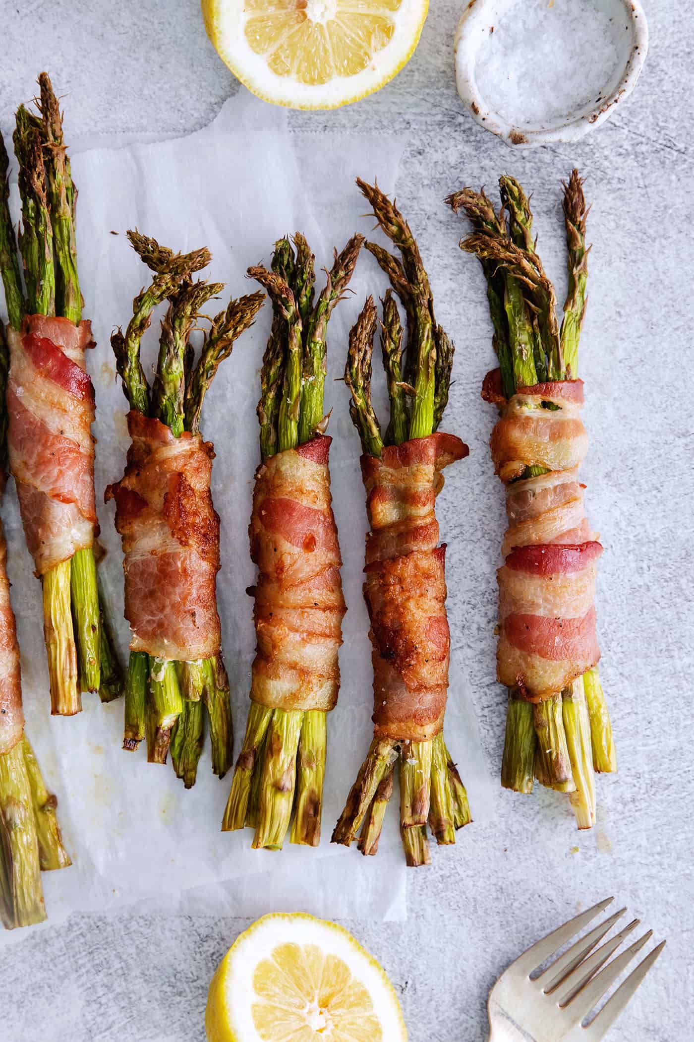 Air Fryer Bacon Wrapped Asparagus is a quick and easy side dish that the whole family is sure to love! 5 ingredients and 15 minutes! Overhead views of bacon wrapped asparagus bundles
