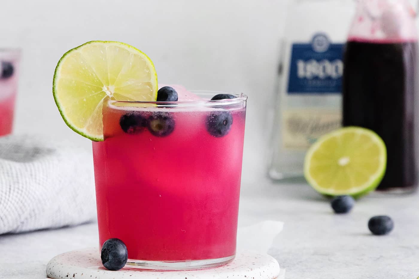 A blueberry margarita garnished with a lime slice