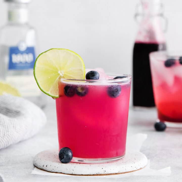 A blueberry margarita garnished with a lime slice