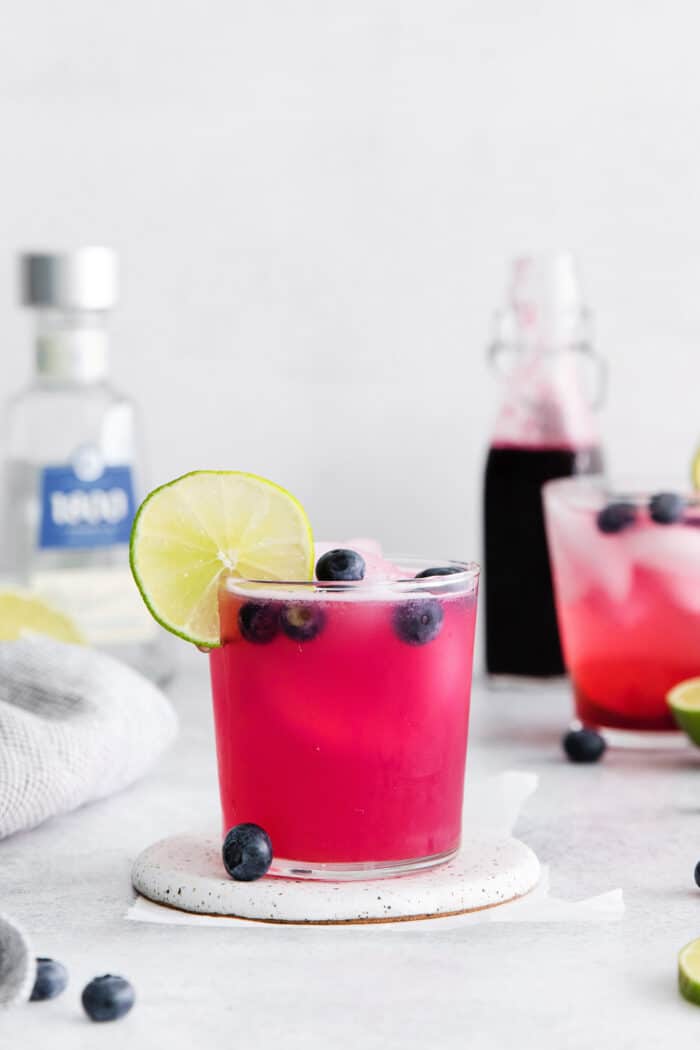 A blueberry margarita garnished with a lime slice