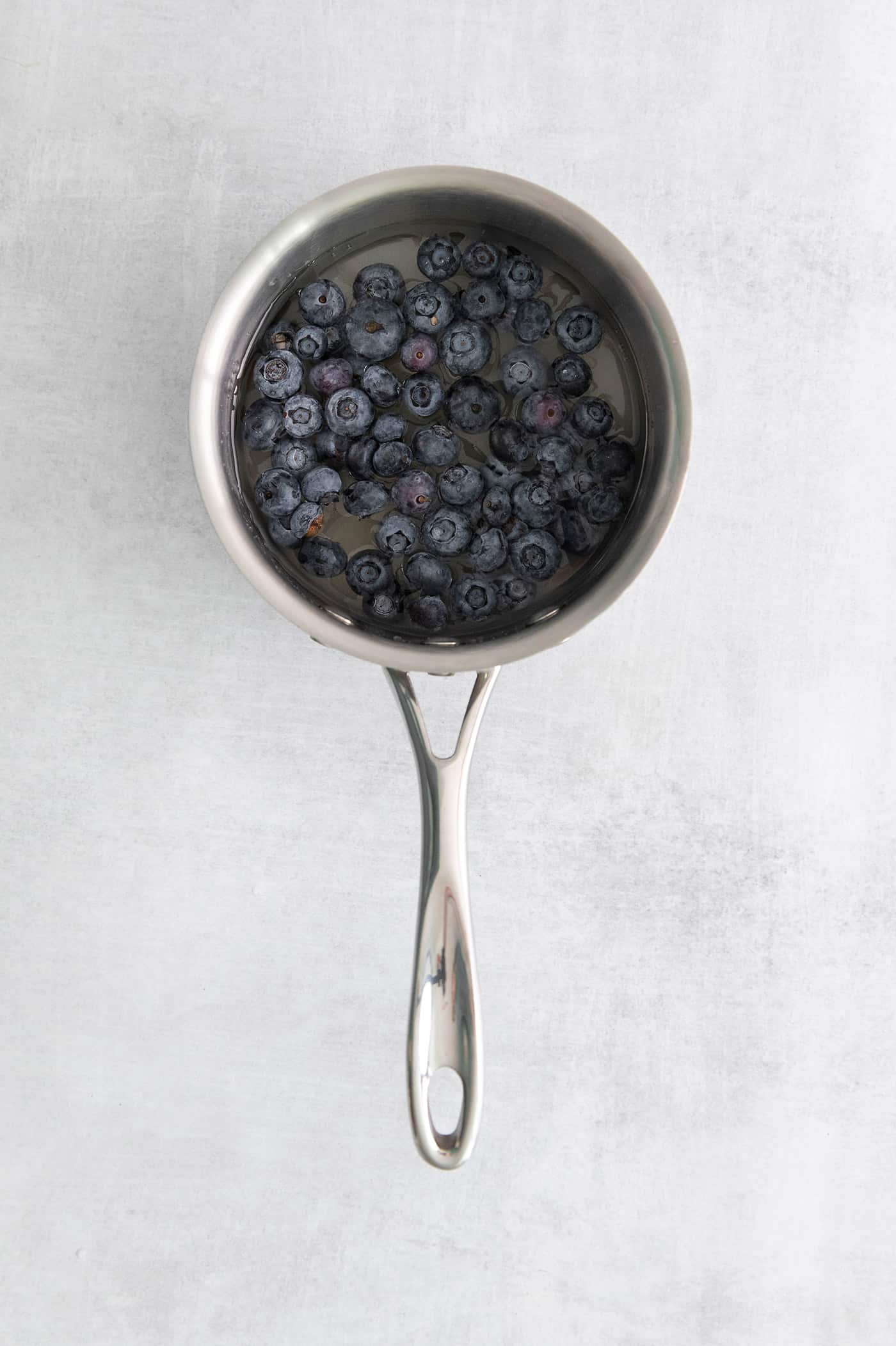Blueberries in a small pan with water and sugar