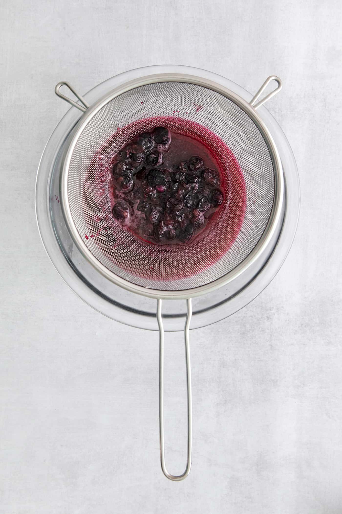 Blueberry syrup being pushed through a strainer