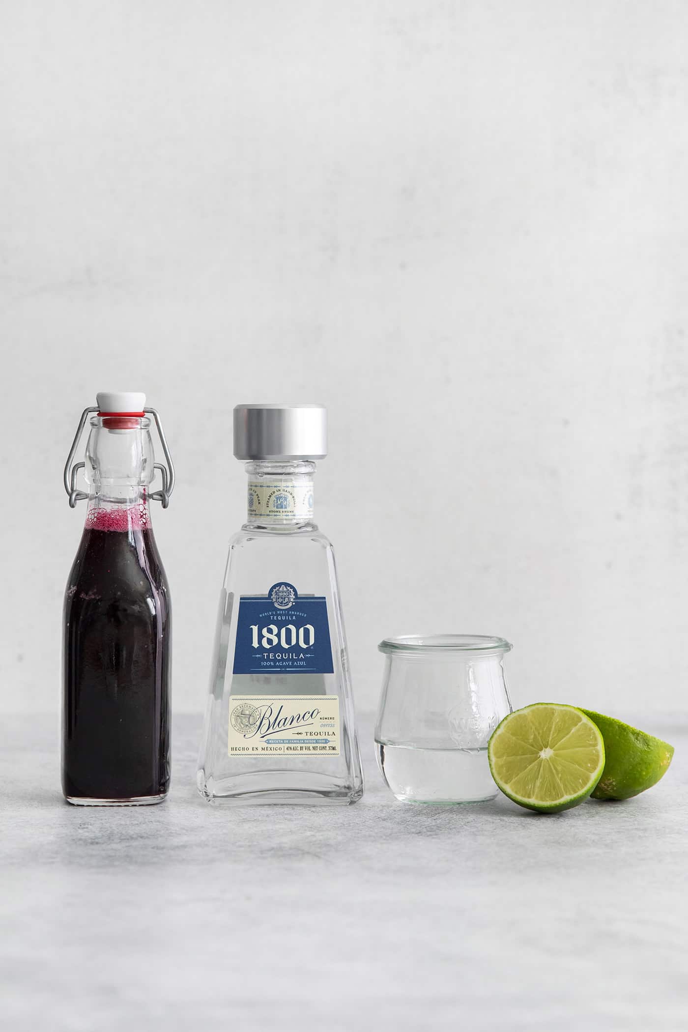 Lime juice being poured into a mason jar with tequila