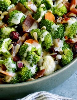 The corner of a bowl of broccoli salad topped with bacon