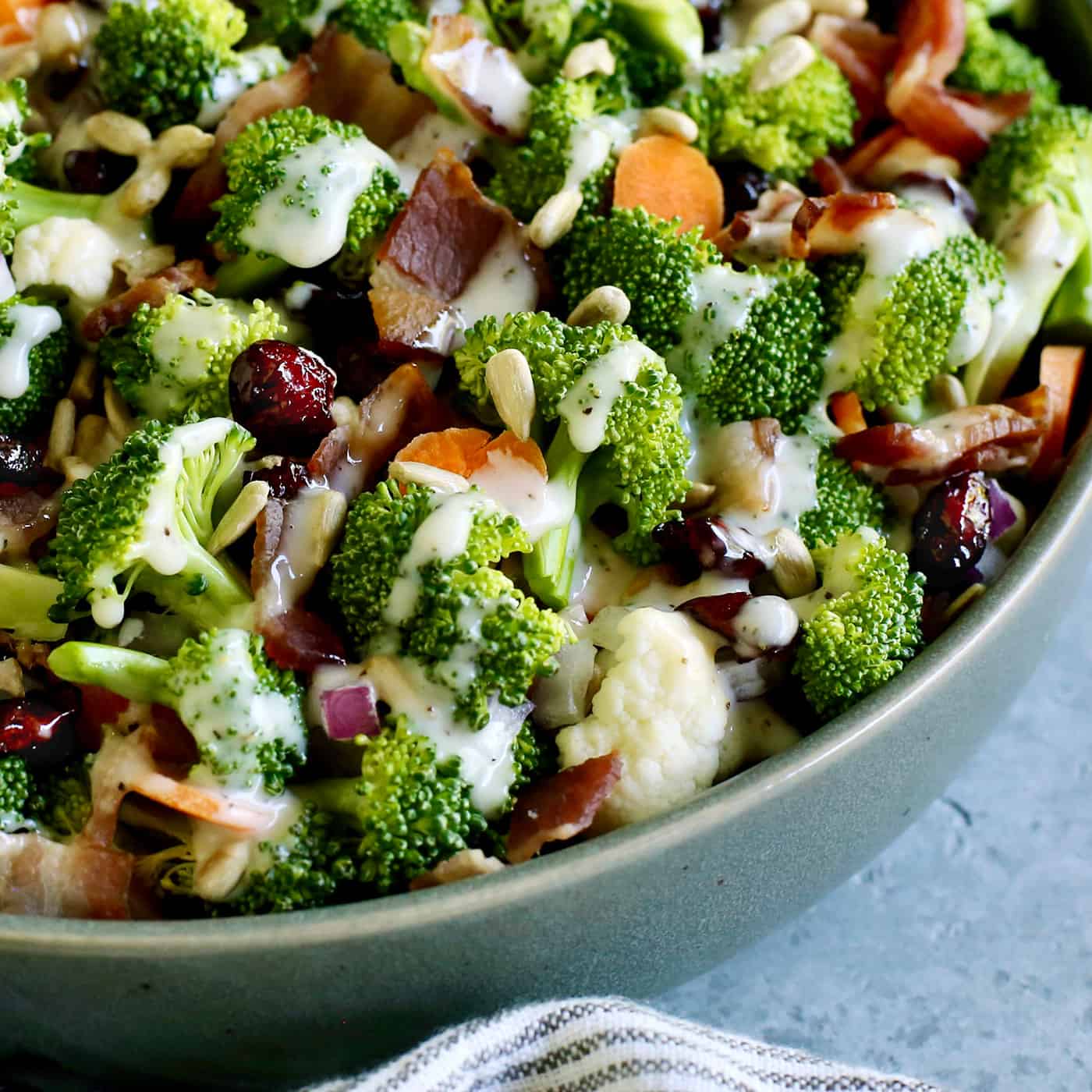 The corner of a bowl of broccoli salad topped with bacon