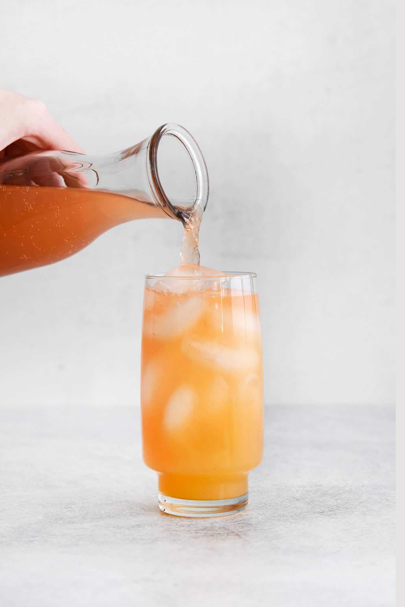 Grapefruit soda being added to a glass with tequila juices and ice