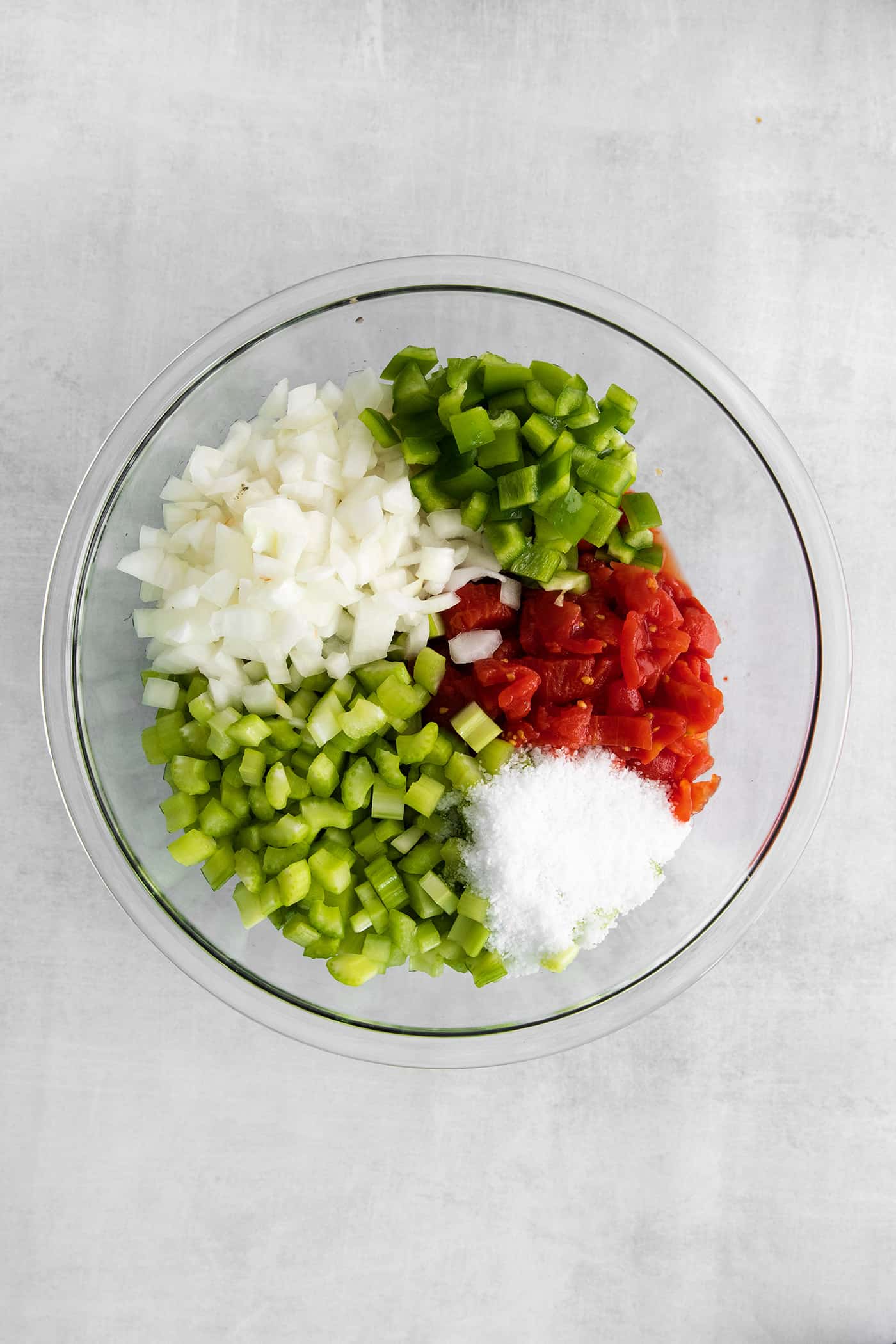 Peppers, tomatoes, celery, and onions in a glass bowl