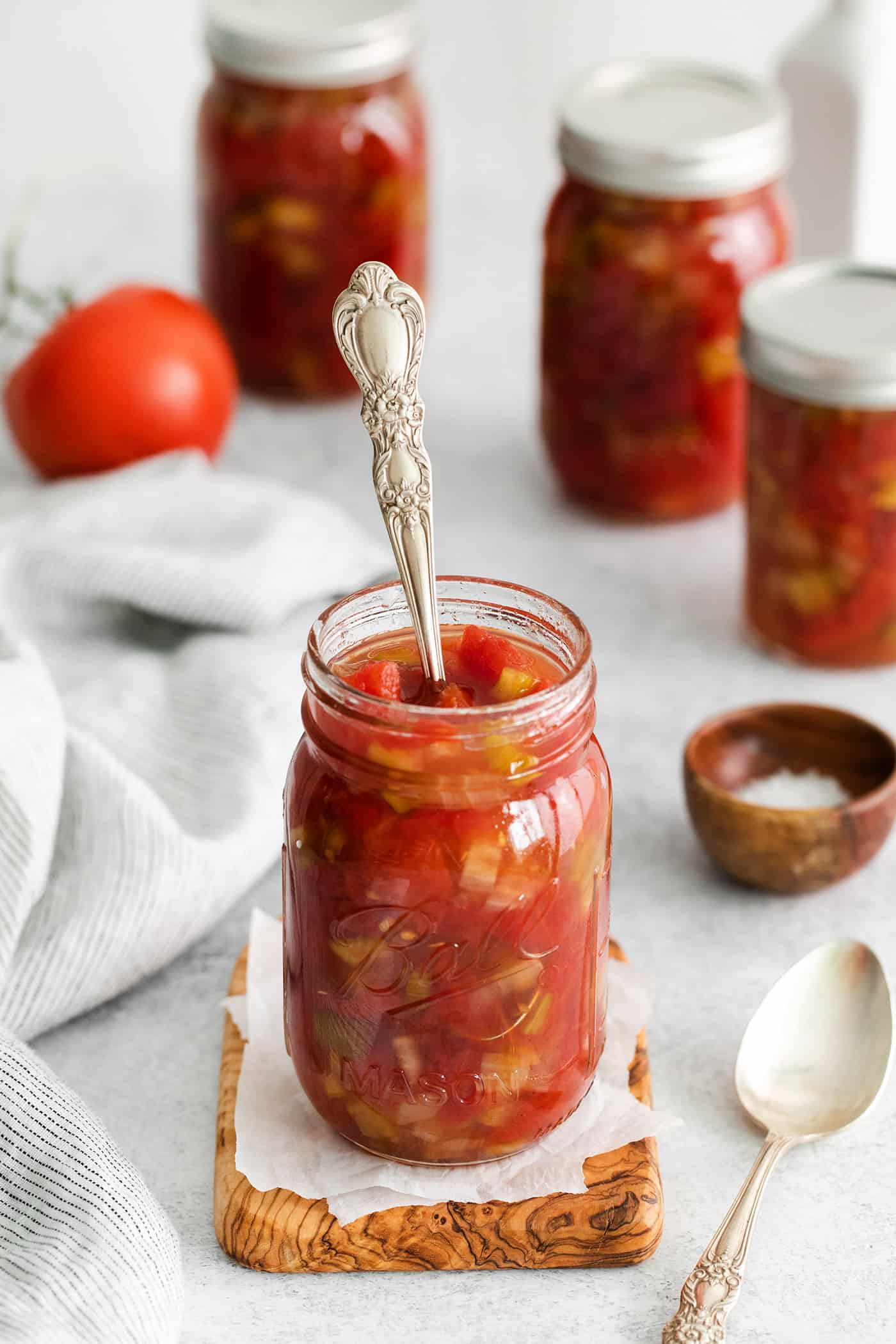 A jar of chili stewed tomatoes with a spoon