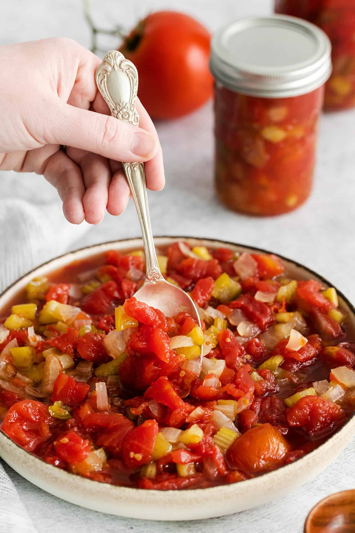 A spoon stirring chili stewed tomatoes