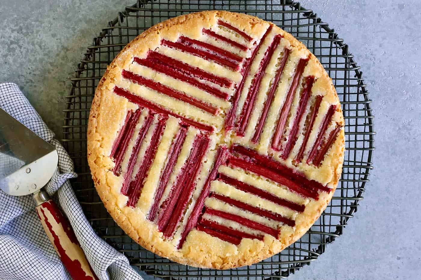 rhubarb custard cake on a a round cooling rack