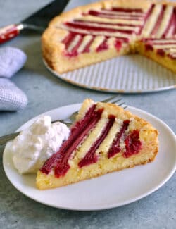 a piece of rhubarb custard cake on a plate, with whipped cream