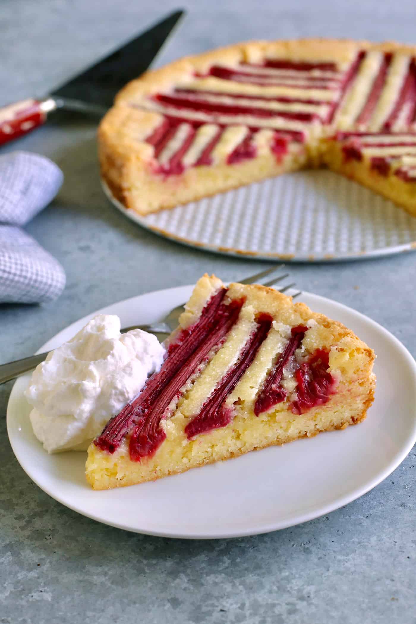 a piece of rhubarb custard cake on a plate, with whipped cream