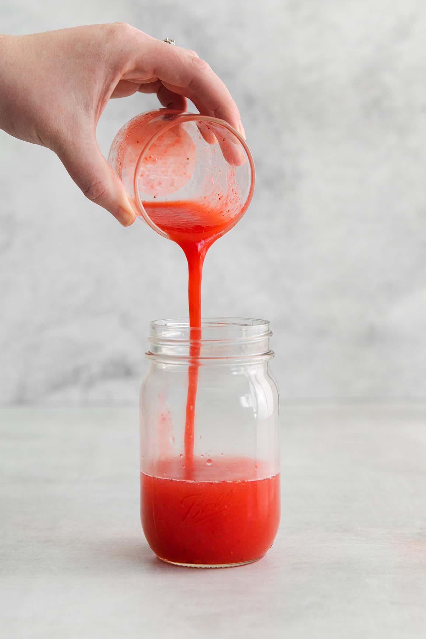 pouring strawberry puree into a jar