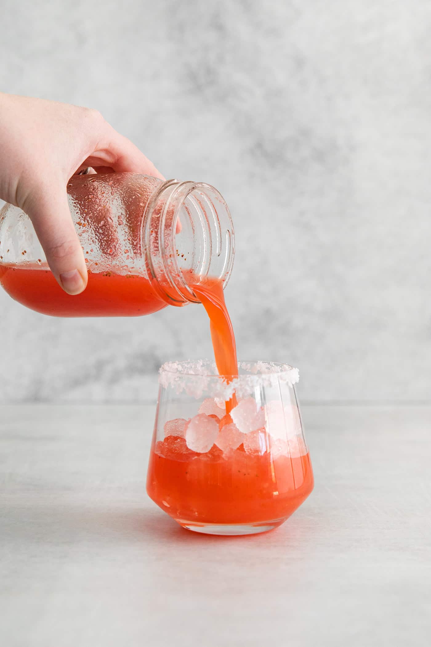 pouring the shaken margarita into an ice-filled glass