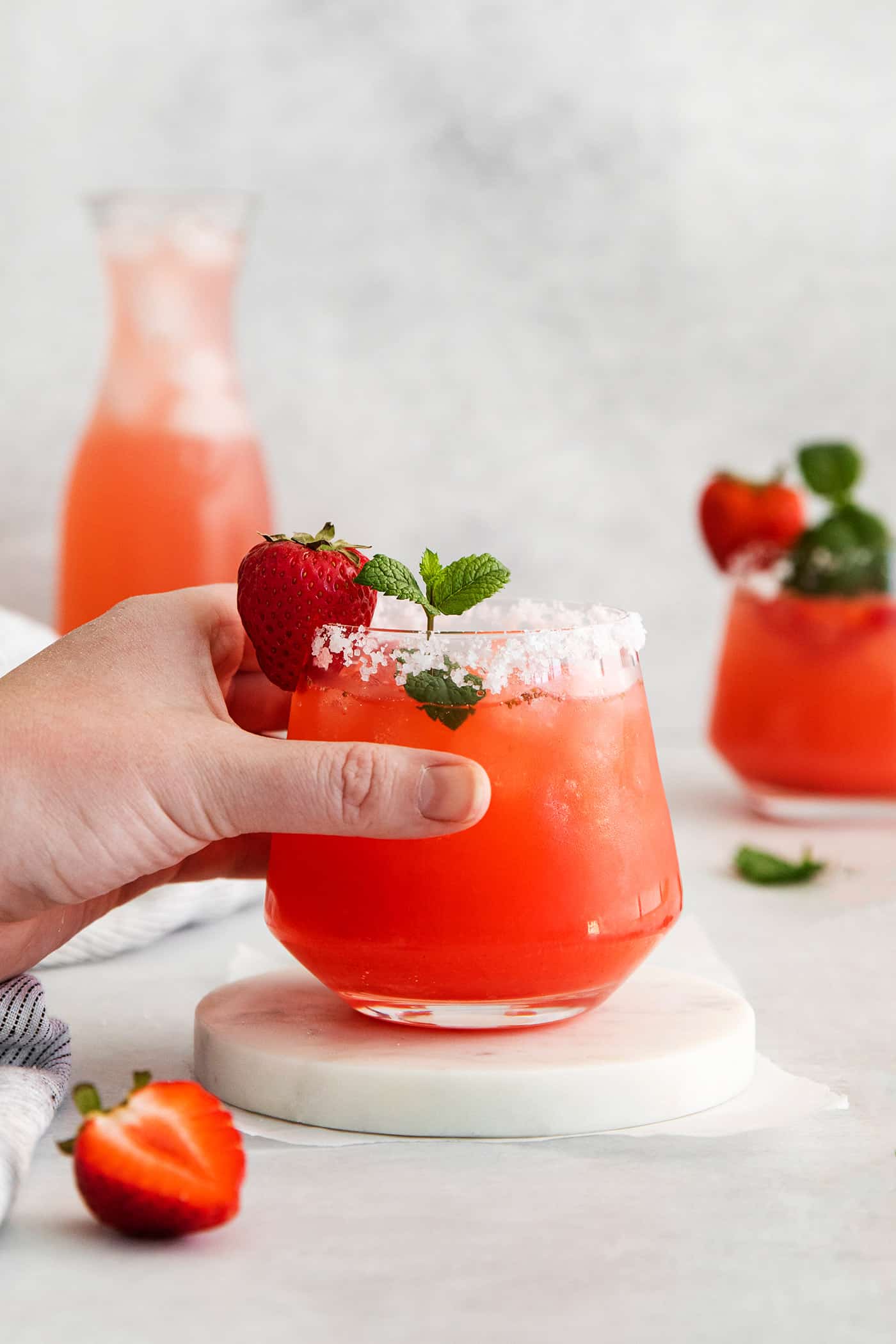 hand holding a glass of margarita with fresh strawberry puree