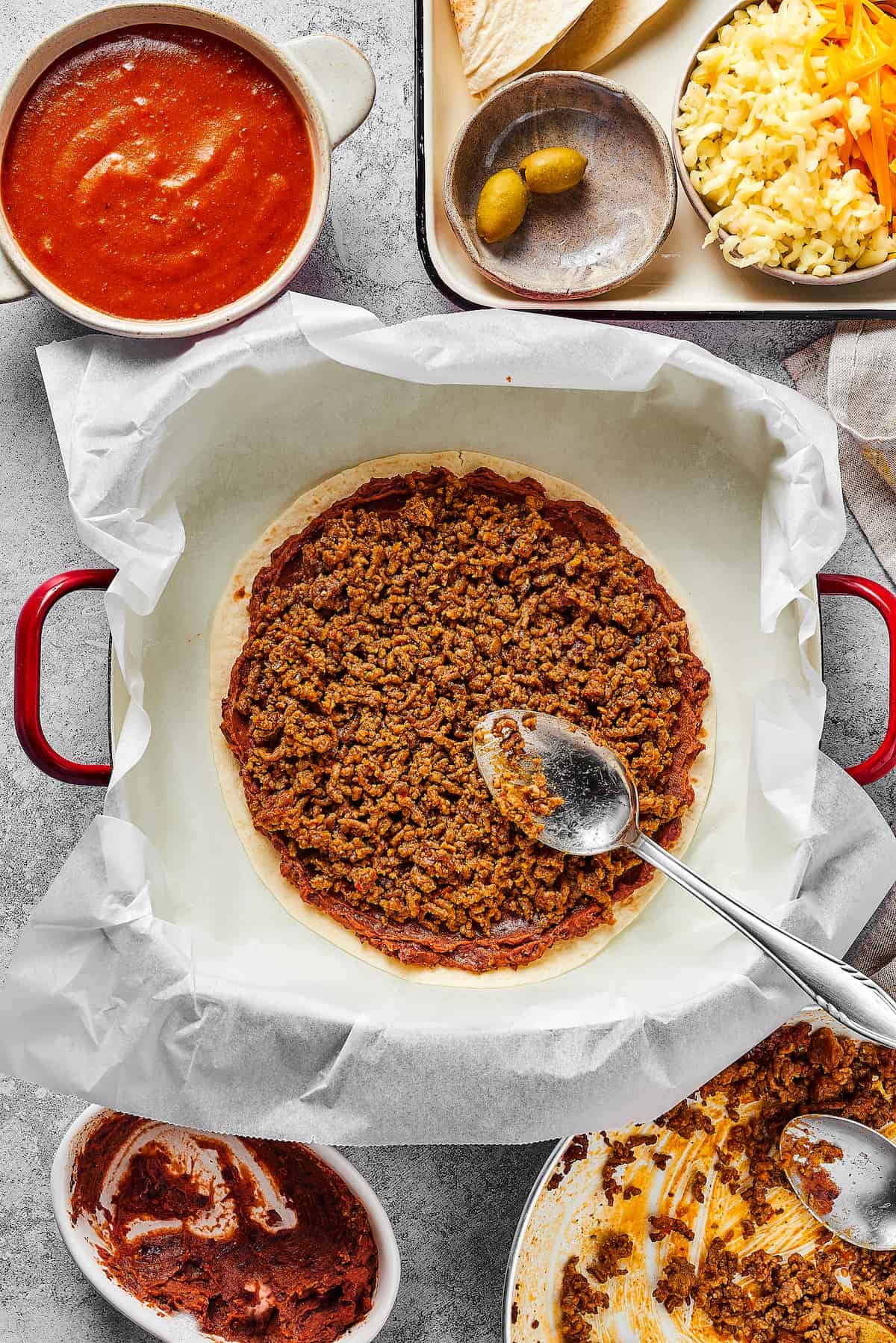 Taco meat and refried beans layered on a tortilla