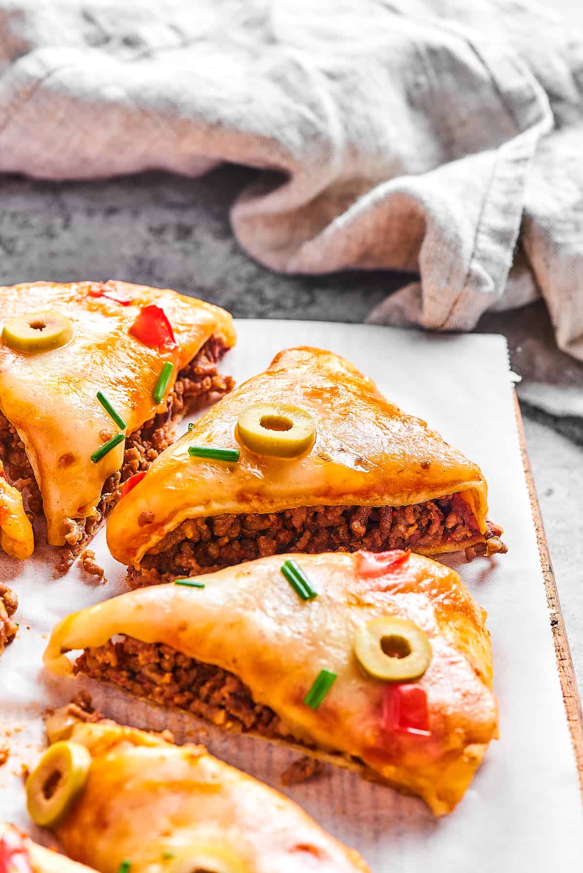 Close-up of triangles of Mexican pizza topped with sliced green olives