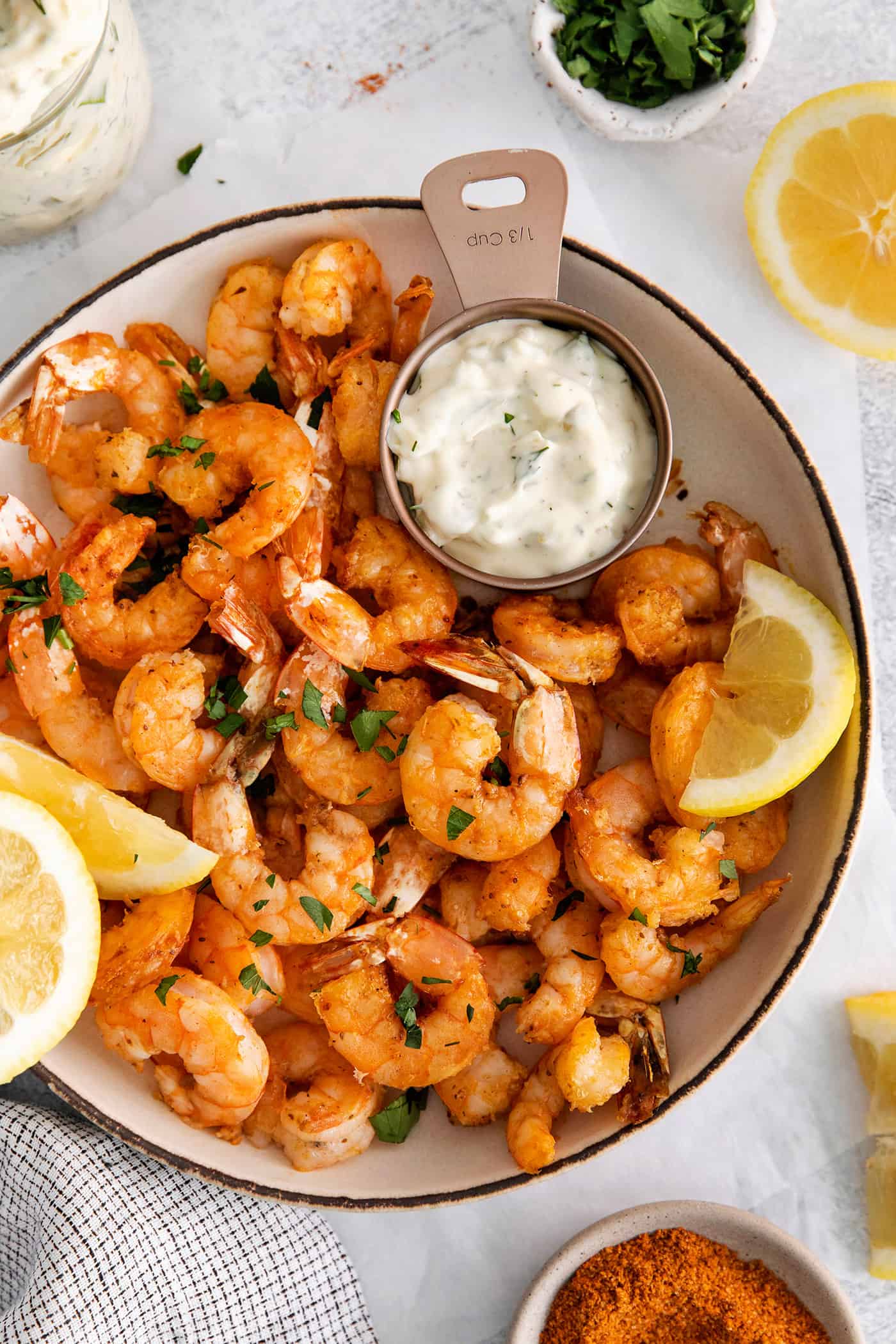 These easy air fryer shrimp are lightly crispy on the outside, tender on the inside, and packed with flavor. Enjoy these with tartar sauce or cocktail sauce, or stuffed into tacos or a salad! Overhead view of a bowl of air fryer shrimp.