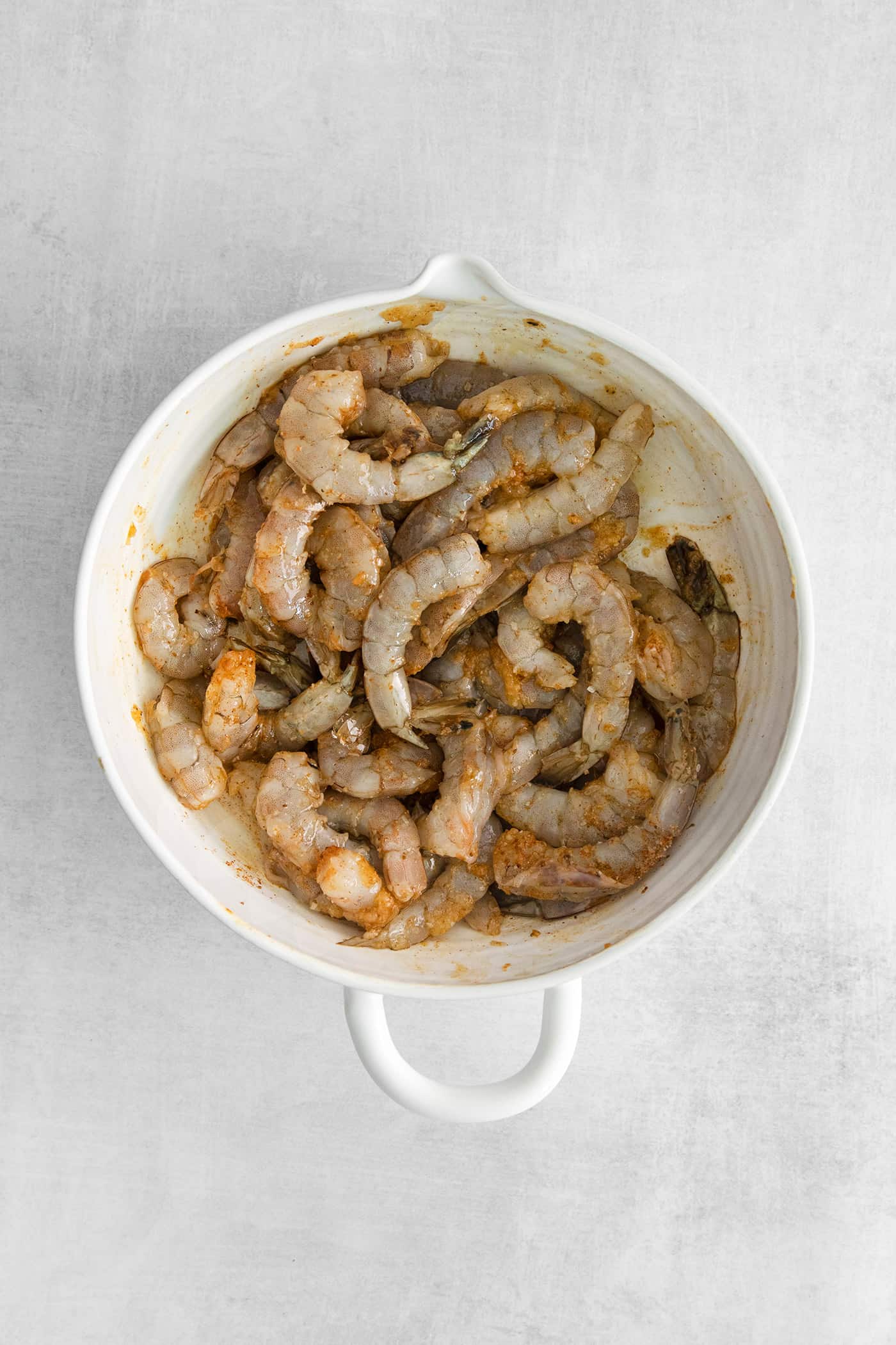 Raw shrimp in a white bowl.