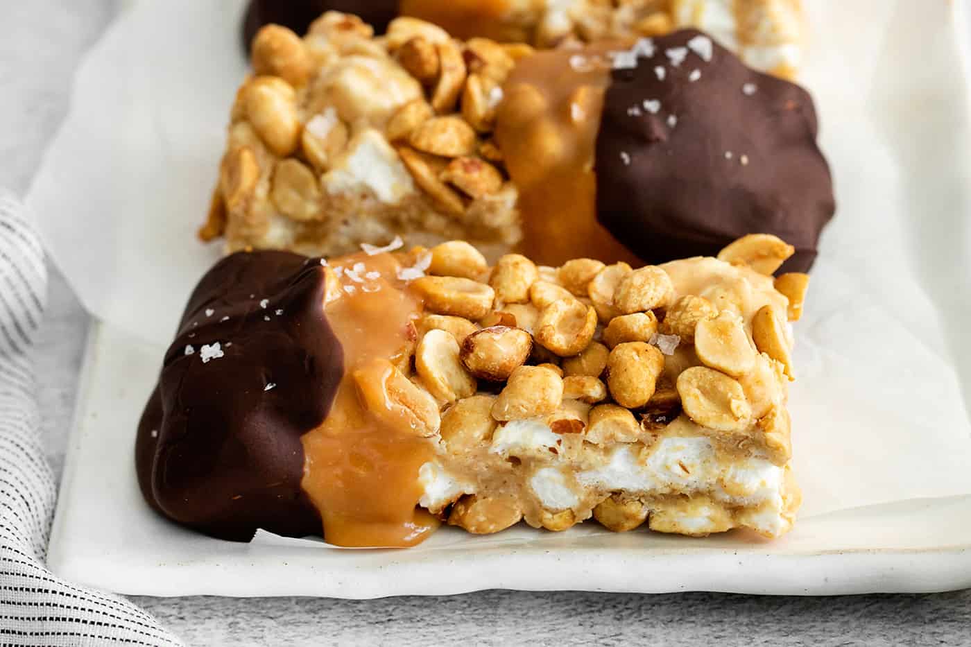 salted nut roll bars dipped in caramel and chocolate on a white plate