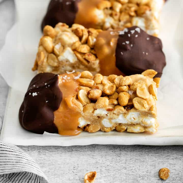 chocolate dipped salted nut roll bars on a white plate