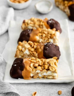a white plate with salted nut roll bars dipped in caramel and chocolate