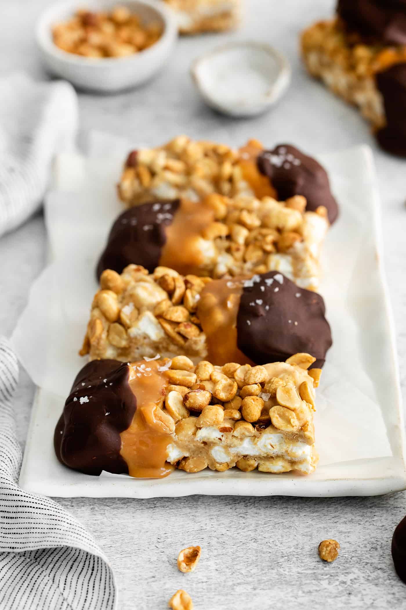 a white plate with salted nut roll bars dipped in caramel and chocolate