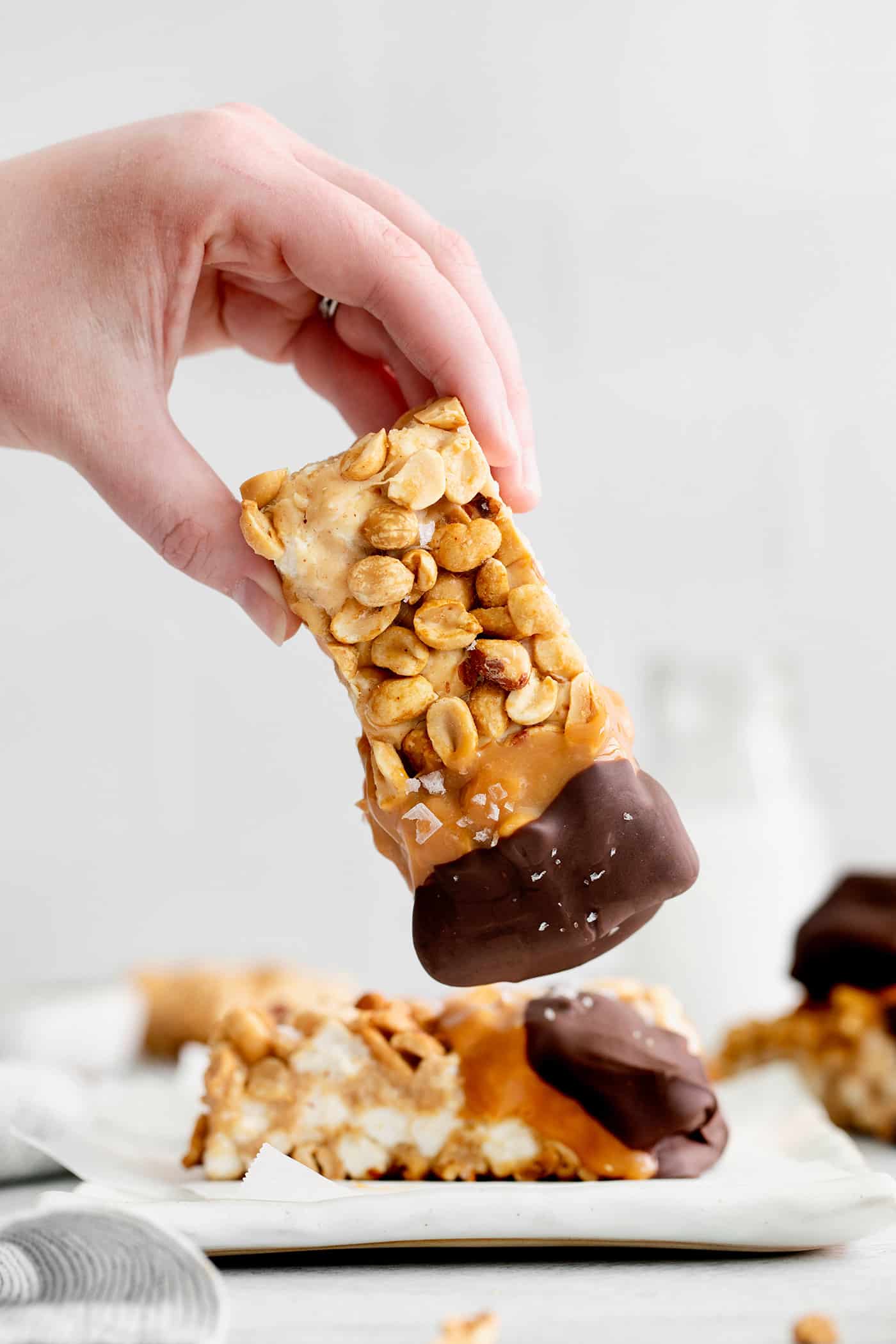 hand holding a chocolate and caramel dipped salted nut roll