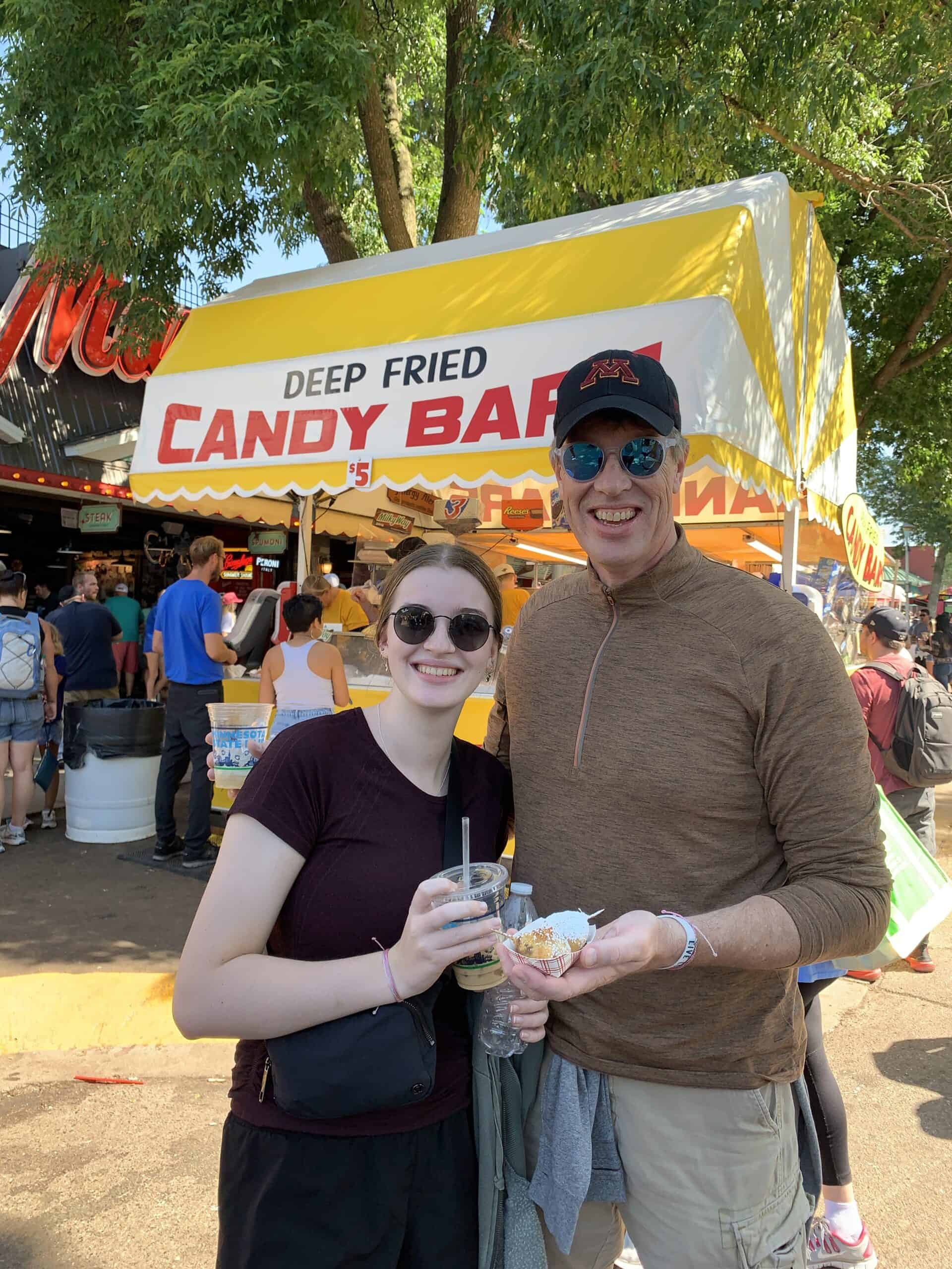 two people holding a deep fried Reese's candy bar