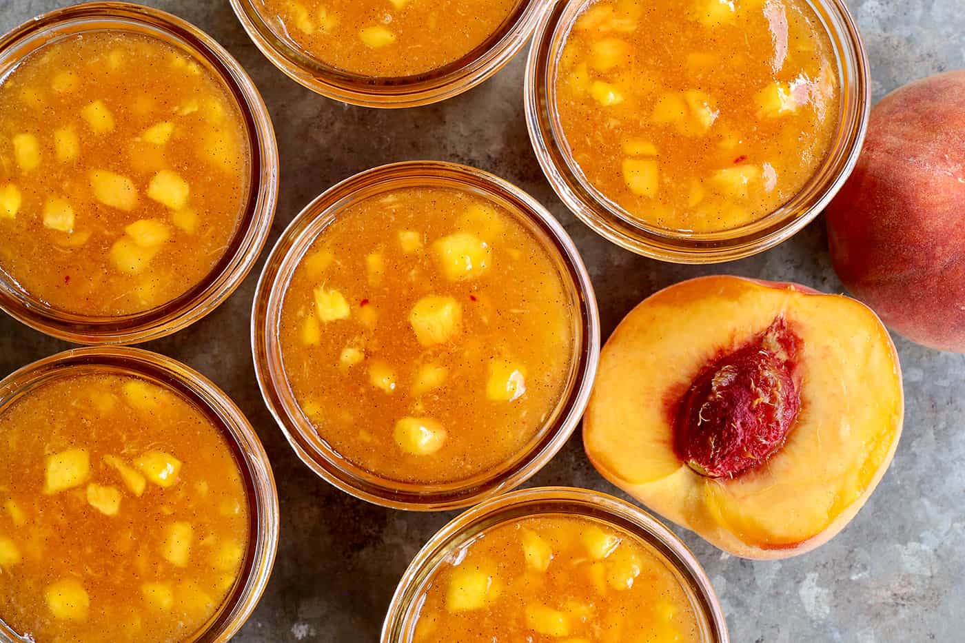 peach freezer jam with vanilla beans in jars with fresh peaches
