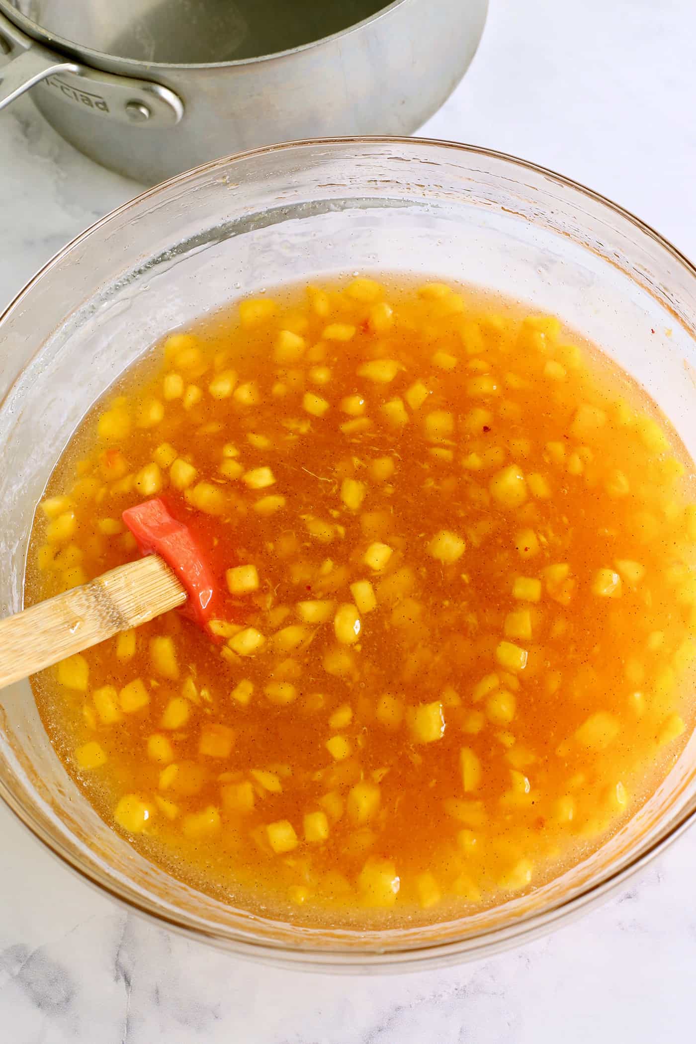 pectin mixture mixed into the fresh peach mixture, in a clear bowl