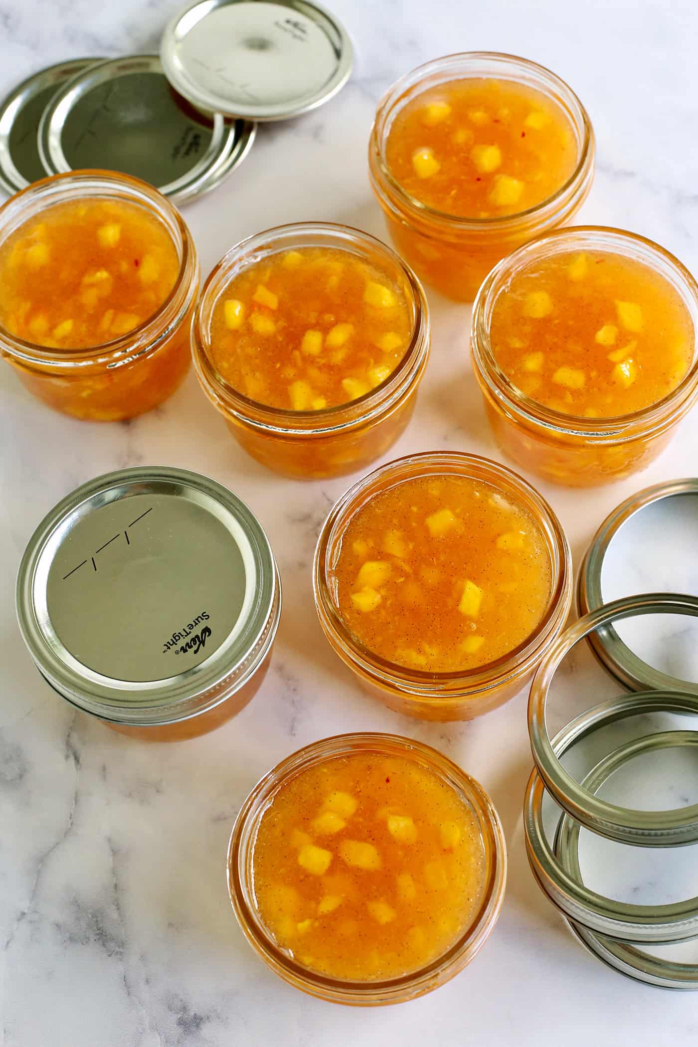 jars filled with peach freezer jam, with lids and rings
