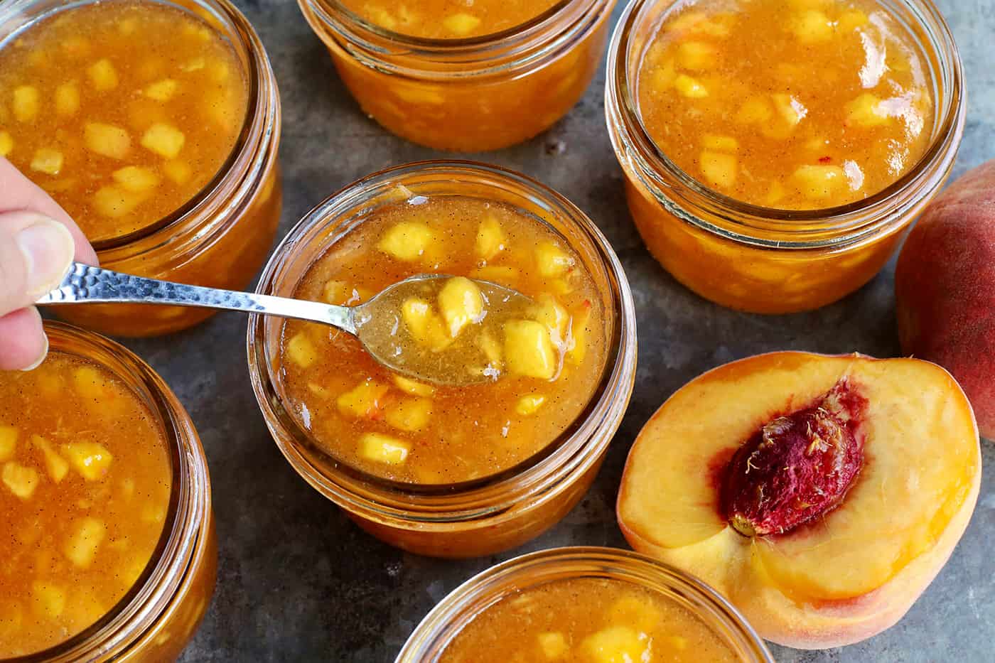 a spoon in a jar of peach vanilla bean jam