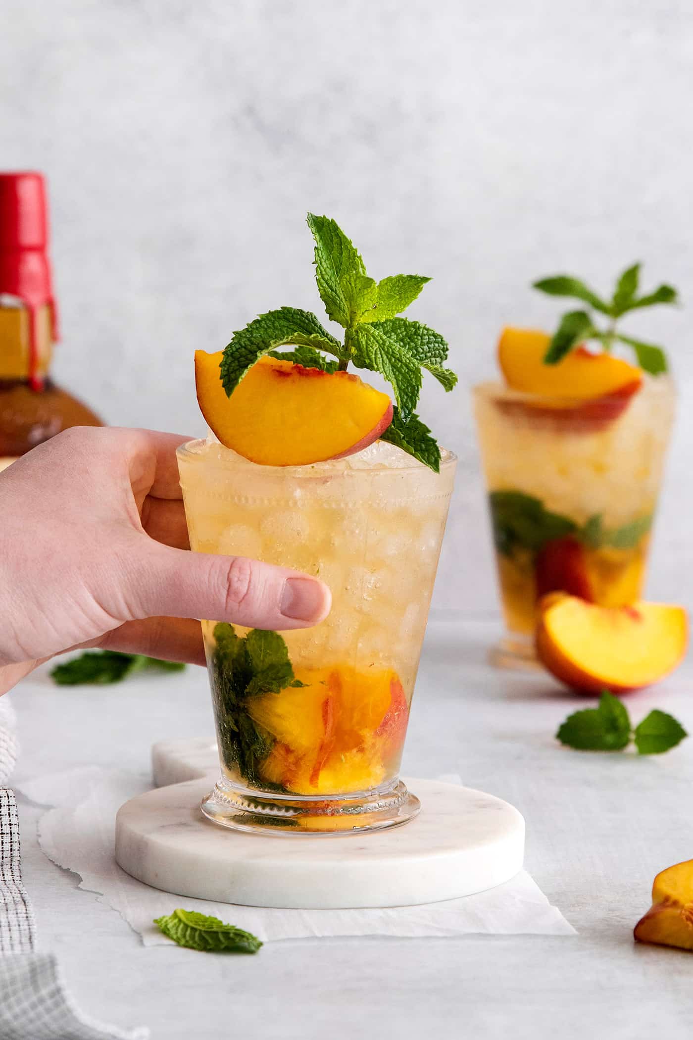A hand grabbing a peach mint julep cocktail