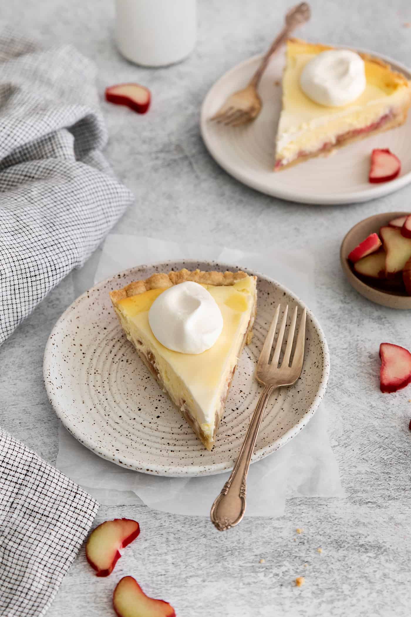 dollops of whipped cream on slices of rhubarb cheesecake pie