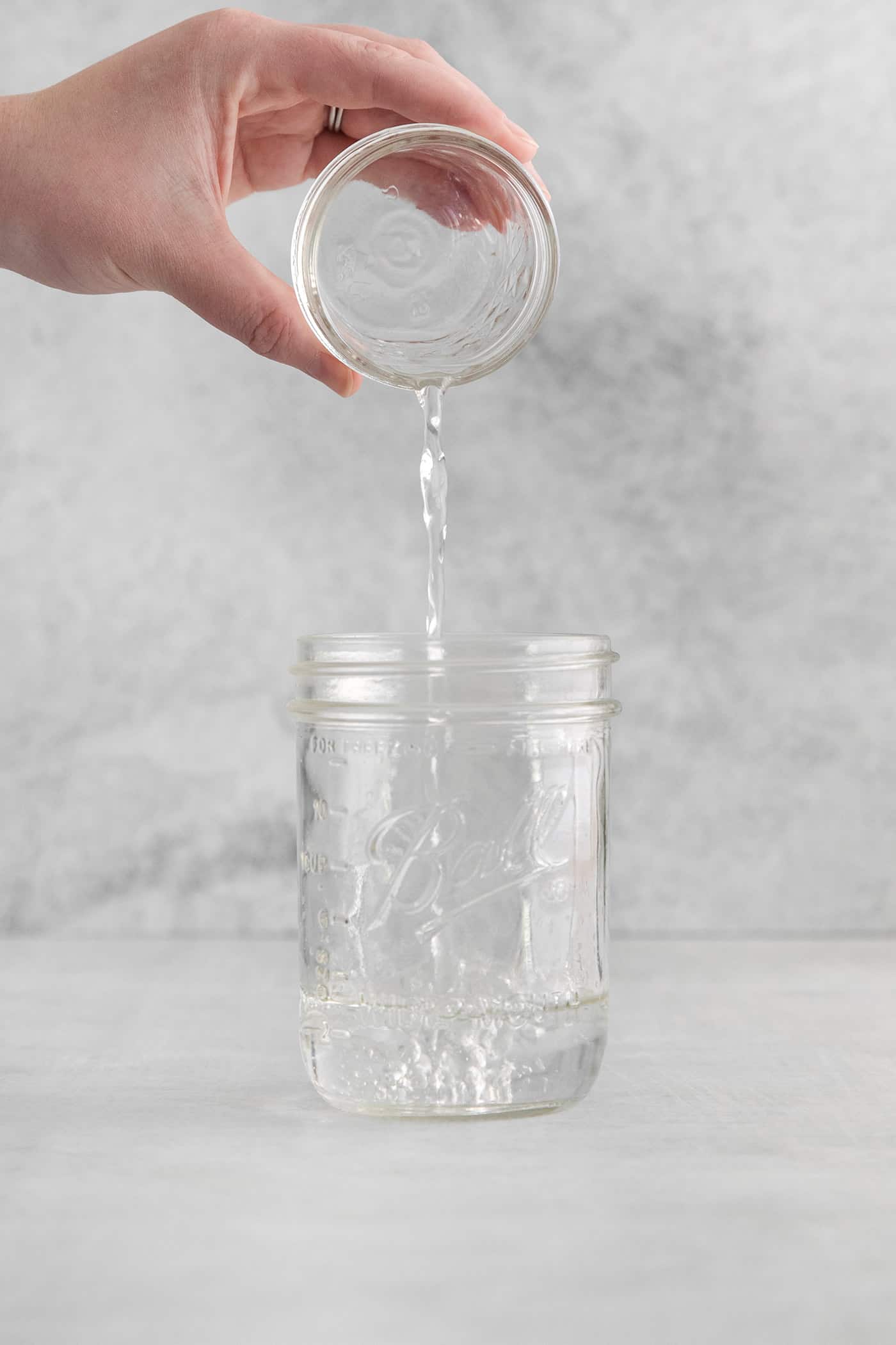 pouring orange liqueur into a jar