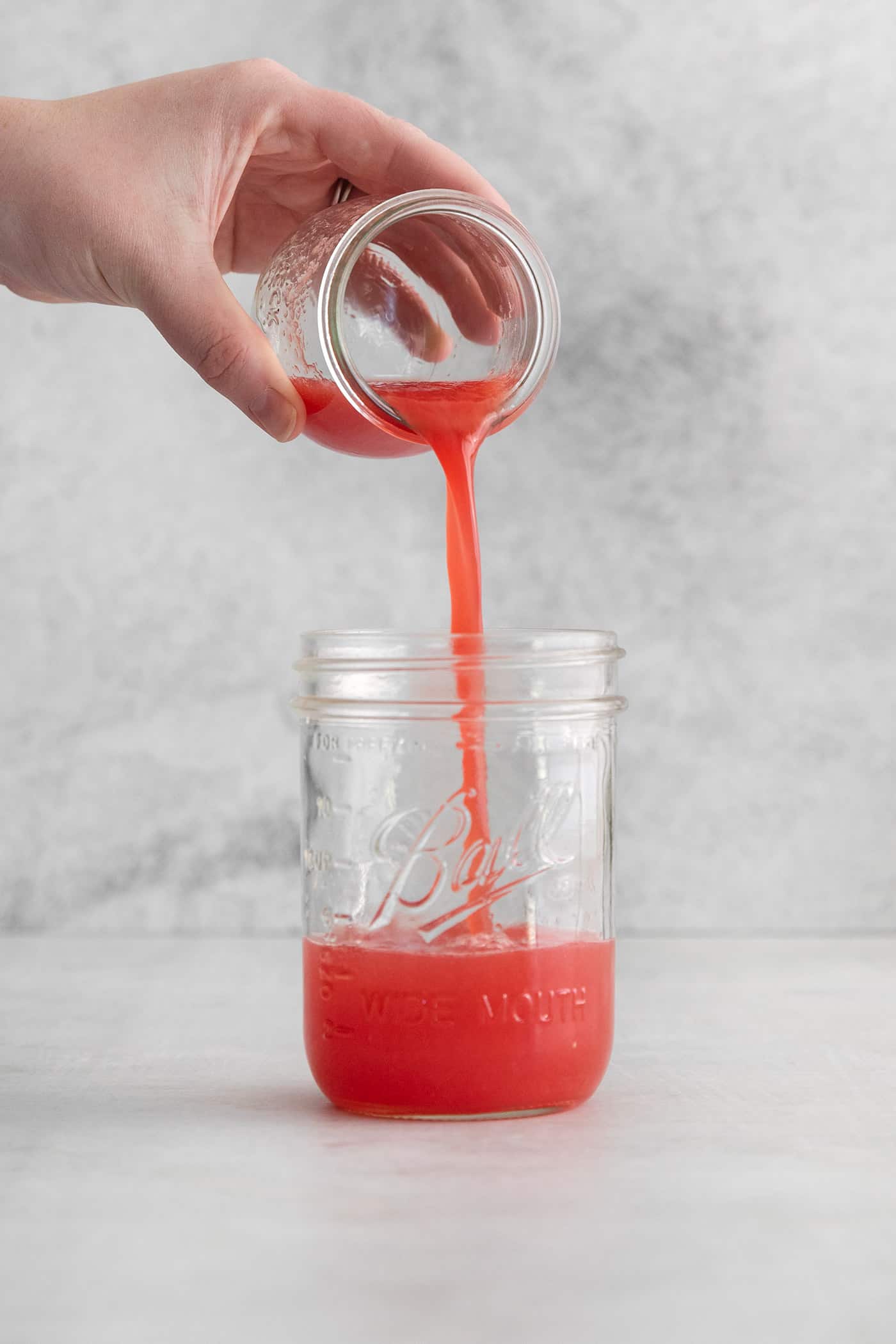 pouring watermelon juice into a jar