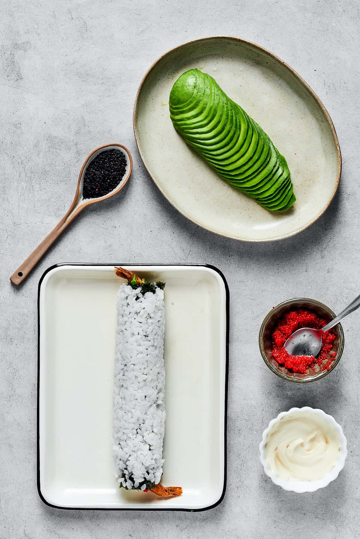 A sushi roll and a plate of avocado slices.
