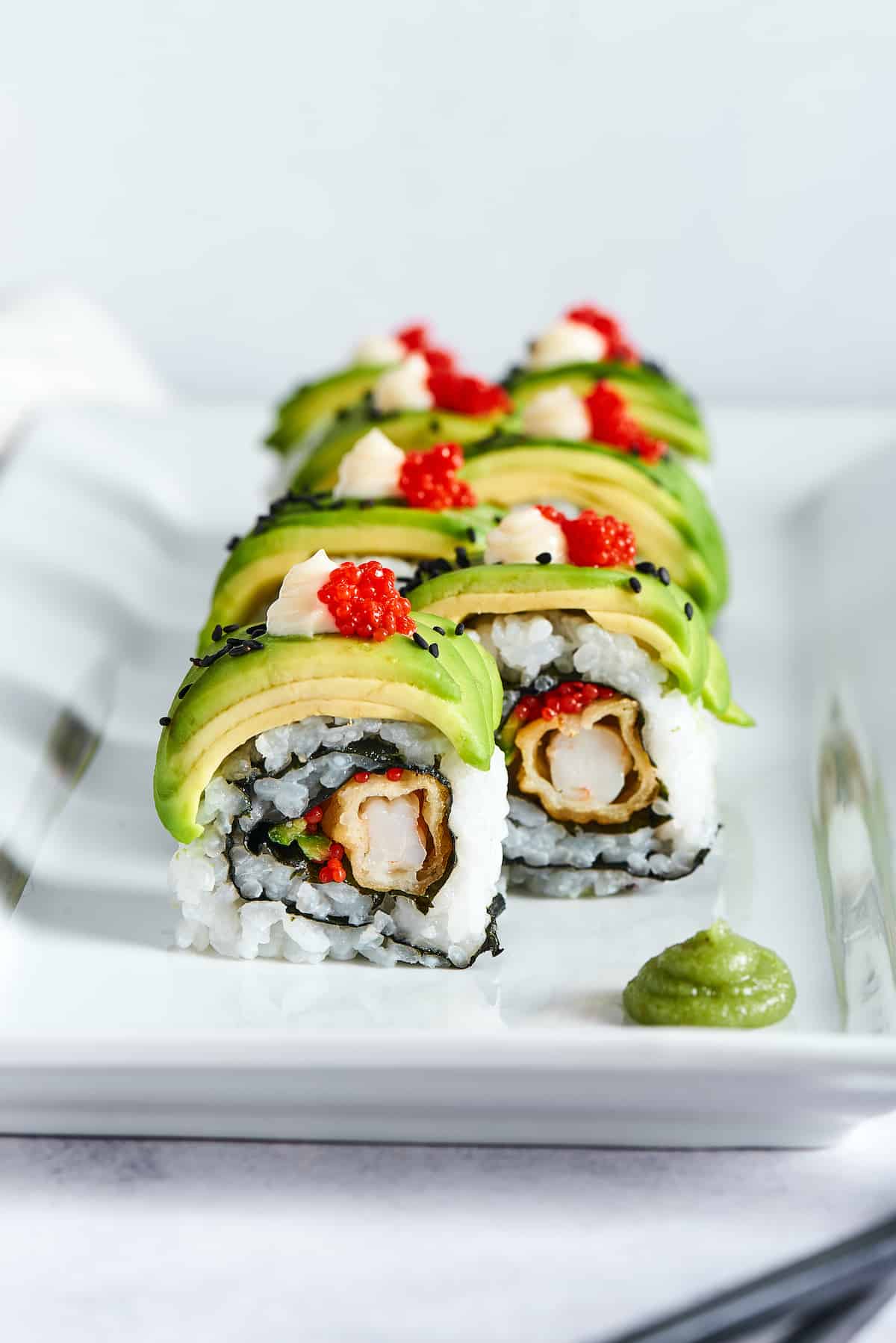 Front view of a dragon roll on a white plate.