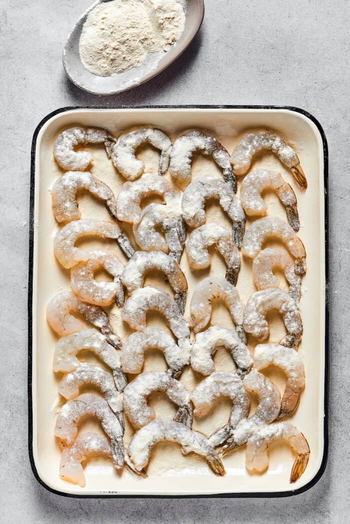 Shrimp coated in flour on a baking sheet