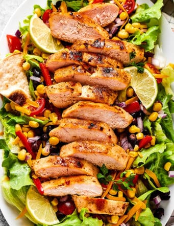 fresh salad greens with sliced grilled chicken on top