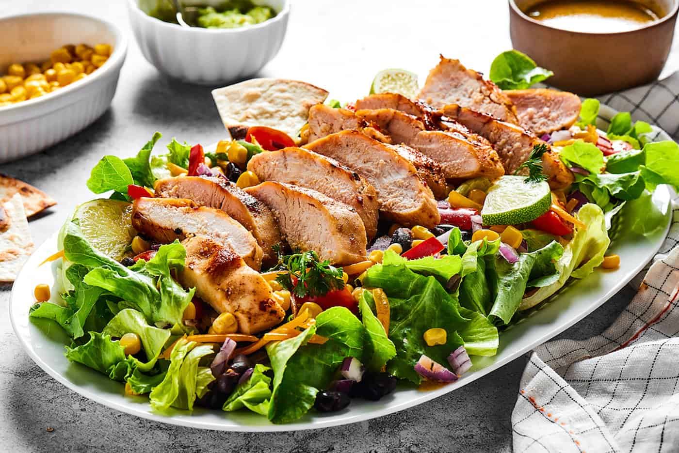 A platter of salad with fresh greens and sliced grilled chicken