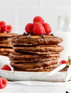 A stack of double chocolate pancakes topped with raspberries