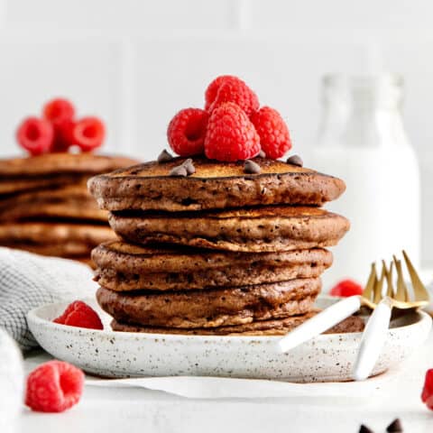 A stack of double chocolate pancakes topped with raspberries