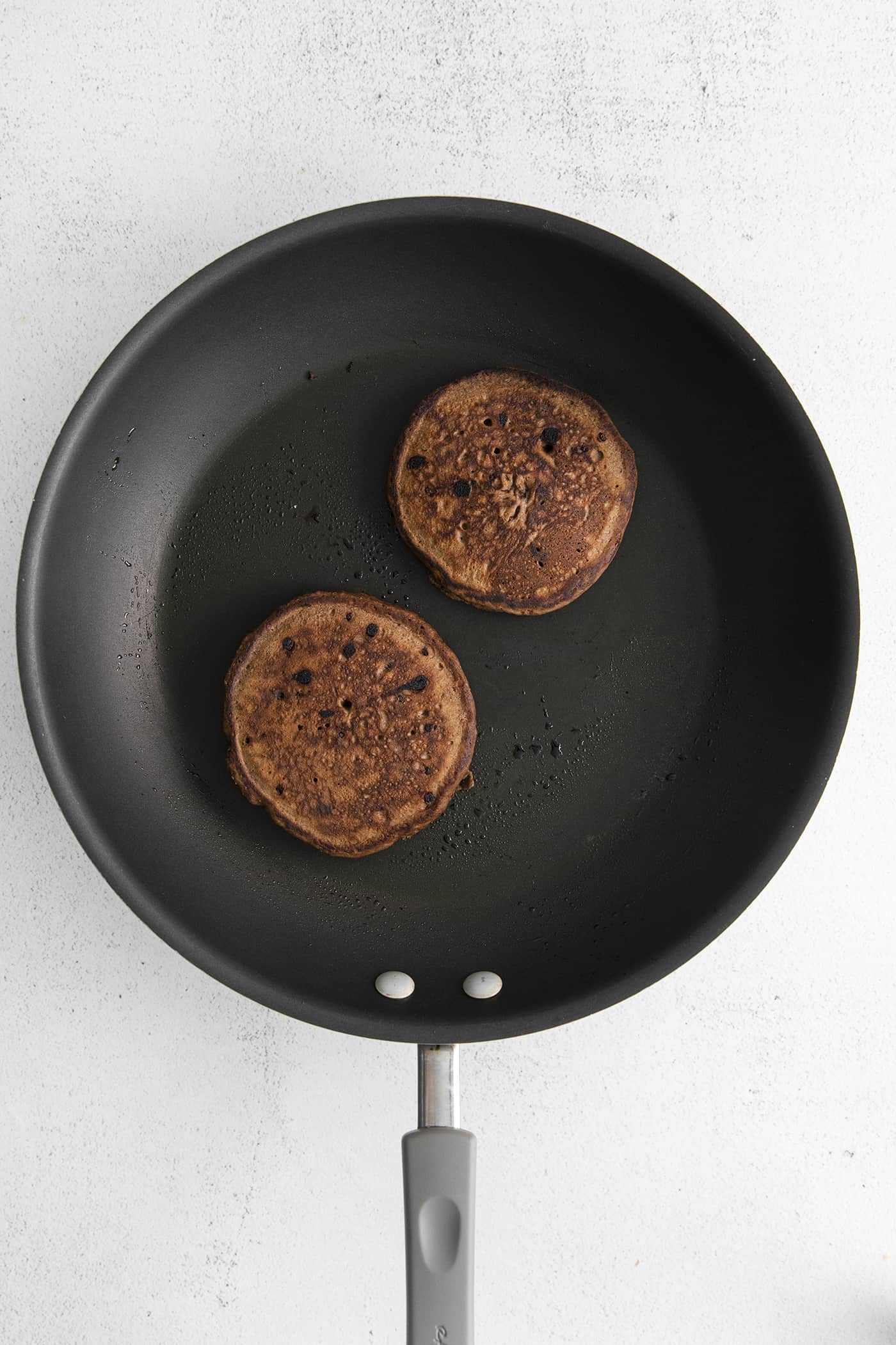 Two chocolate pancakes in a skillet