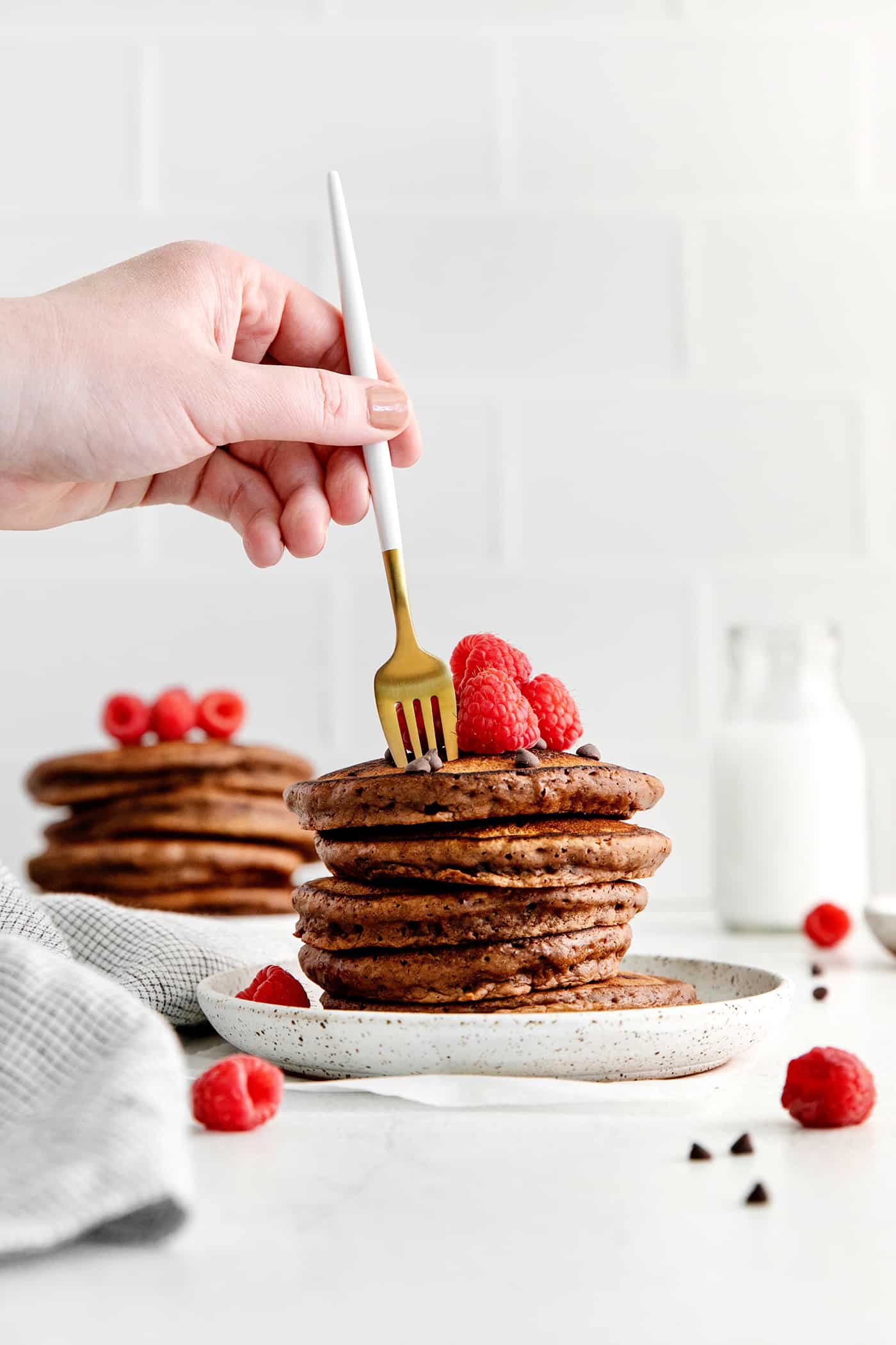 A fork diving into a stack of chocolate pancakes